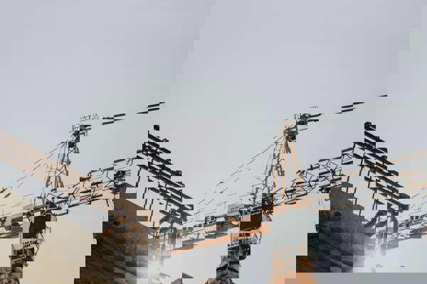 Construction site with yellow crane and scaffolding under bright sunlight.